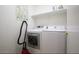 This laundry room has a white front load washer and dryer, with a shelf at 20218 N 61St Ave, Glendale, AZ 85308