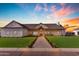 Beautifully designed home with a covered porch, complemented by lush green lawn and colorful sunset at 2312 N Raven --, Mesa, AZ 85207