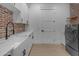 Bright laundry room features a white farmhouse sink, brick accent wall, and modern washer and dryer at 2312 N Raven --, Mesa, AZ 85207