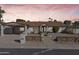 A charming home featuring a desert landscape, carport, and mature trees, illuminated in the evening light at 2366 E Shea Blvd, Phoenix, AZ 85028