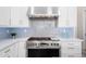 Close-up of a kitchen range with stainless steel vent hood and blue backsplash tiles at 3045 W Feather Sound Dr, Anthem, AZ 85086