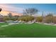 Beautiful backyard featuring artificial turf, rock water feature, lounge chairs, and desert landscaping at 42001 N Bridlewood Way, Phoenix, AZ 85086