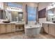 Traditional primary bathroom with marble tiled surround soaking tub, dual vanities and window at 42001 N Bridlewood Way, Phoenix, AZ 85086
