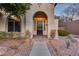 Charming home featuring an arched entryway, dark wood door, desert landscaping, and a welcoming walkway at 42001 N Bridlewood Way, Phoenix, AZ 85086