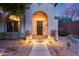 Charming home featuring an arched entryway, dark wood door, desert landscaping, and a welcoming walkway at 42001 N Bridlewood Way, Phoenix, AZ 85086