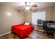 Bedroom with a ceiling fan, modern desk, and computer setup, with a red bedspread at 502 N 110Th St, Mesa, AZ 85207