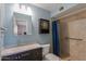 Cozy bathroom featuring a shower, vanity with dark wood cabinets, and blue walls at 6319 E Duncan St, Mesa, AZ 85205