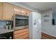 Kitchen area featuring wood cabinets, stainless-steel microwave, and a white refrigerator at 6319 E Duncan St, Mesa, AZ 85205