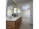 Bright bathroom featuring a double sink vanity with warm wood cabinets and an open doorway to the Primary bedroom at 9318 E El Paso St, Mesa, AZ 85207