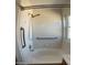 Bright white tiled bathtub and shower combination with safety bars and window at 9318 E El Paso St, Mesa, AZ 85207