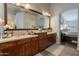 Large main bathroom vanity with dual sinks, dark wood cabinetry, light countertops, and a large decorative mirror at 10431 N 55Th Pl, Paradise Valley, AZ 85253