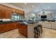 Open kitchen and living area with wooden cabinets, island with bar seating, and a cozy fireplace at 10431 N 55Th Pl, Paradise Valley, AZ 85253