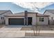 Charming single-story home features stone accents and a dark green garage door, set against a bright blue sky at 17793 W Southgate Ave, Goodyear, AZ 85338