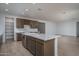 Modern kitchen with white island, stainless steel appliances, ample cabinet space, and wood-look tile flooring at 17793 W Southgate Ave, Goodyear, AZ 85338
