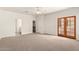 Spacious bedroom featuring neutral walls, a ceiling fan, and glass paneled doors to the outside at 20329 E Bronco Dr, Queen Creek, AZ 85142