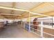 Indoor view of horse stalls, metal fencing, and horses in a well-maintained equestrian facility at 20329 E Bronco Dr, Queen Creek, AZ 85142