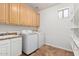 Laundry room with wood cabinets, white appliances, stainless steel sink, and tiled floors at 20329 E Bronco Dr, Queen Creek, AZ 85142