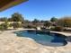 Inviting backyard pool surrounded by a stone patio, lush landscaping, and a secure wrought iron fence at 27621 N 174Th Dr, Surprise, AZ 85387
