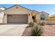 Tan single-story home with three-car garage, desert landscaping, and covered entry way at 27621 N 174Th Dr, Surprise, AZ 85387