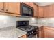 Close-up shot of black gas range and built-in microwave, set against granite countertops and stylish wood cabinets at 27621 N 174Th Dr, Surprise, AZ 85387
