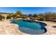 Inviting backyard pool features flagstone deck, accent wall, and black metal safety fence at 27621 N 174Th Dr, Surprise, AZ 85387