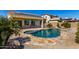 Backyard pool with stone trim is surrounded by desert landscaping and features solar panels above covered patio at 27621 N 174Th Dr, Surprise, AZ 85387