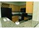 Galley style kitchen featuring wood cabinetry, granite countertops, and black appliances at 2929 W Yorkshire Dr # 1028, Phoenix, AZ 85027
