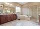 Bright bathroom featuring dual sinks, a soaking tub, walk-in shower, and elegant marble tiling at 30056 N 129Th Ave, Peoria, AZ 85383
