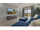 Relaxing living room with a blue sofa, TV, and a sliding glass door leading to the balcony at 11036 E Evans Rd, Scottsdale, AZ 85255