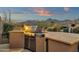 Built-in outdoor kitchen area with grill and ample counter space for food preparation, set against a picturesque desert landscape at 11036 E Evans Rd, Scottsdale, AZ 85255