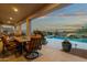 Serene poolside area with an outdoor dining set, surrounded by lush greenery and a view of distant mountains at 11036 E Evans Rd, Scottsdale, AZ 85255