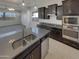 Well-lit kitchen featuring dark wood cabinets, stainless steel appliances, and an island with a double sink at 12164 S 184Th Ave, Goodyear, AZ 85338