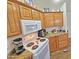 The cozy kitchen features wood cabinetry, granite countertops, and white appliances at 124 S 54Th St # 42, Mesa, AZ 85206
