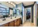 Well-lit bathroom with double sinks, tile floors, and a view into the walk-in closet at 14532 N 146Th Ln, Surprise, AZ 85379