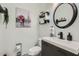 Stylish half-bathroom featuring modern fixtures, a round mirror, and decorative artwork at 14532 N 146Th Ln, Surprise, AZ 85379
