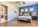 Bright bedroom features wood floors, a blue accent wall, and view into ensuite bathroom at 30227 N 124Th Dr, Peoria, AZ 85383