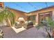 Inviting outdoor patio with a brick fireplace, ample seating, and lush greenery under ambient string lights at 30227 N 124Th Dr, Peoria, AZ 85383