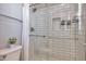 Modern shower with white subway tile, glass door, shower niche, and a sleek shower head, complemented by stylish hardware at 30227 N 124Th Dr, Peoria, AZ 85383