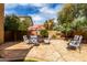 Inviting backyard featuring a stone patio with outdoor seating and mature trees, great for outdoor living and relaxation at 32795 N Hidden Canyon Dr, San Tan Valley, AZ 85144