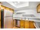 Functional kitchen featuring stainless steel appliances, wooden cabinetry, laminate countertops, and tile flooring at 4482 W Palmaire Ave, Glendale, AZ 85301