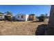 A view of a single-story home's backyard with a dirt lot, miscellaneous building materials, and a bush at 508 S 98Th St, Mesa, AZ 85208