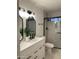 Modern bathroom featuring a double sink vanity, black hardware, decorative mirrors, and a glass-enclosed shower at 8201 W Tuckey Ln, Glendale, AZ 85303