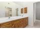 Bathroom featuring double sink vanity with warm wood cabinets and large mirror at 8310 W Daley Ln, Peoria, AZ 85383