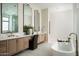 Elegant bathroom showcasing dual vanities with marble countertops, soaking tub, and refined fixtures with sleek mirrors at 10220 N 66Th St, Paradise Valley, AZ 85253