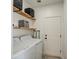 Bright laundry room with modern washer and dryer, wood shelves, and utility sink at 14132 W Bent Tree S Cir, Litchfield Park, AZ 85340