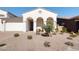 Charming home exterior with arched entry, desert landscaping, and a cozy bench on the front porch at 17816 W Oregon Ave, Litchfield Park, AZ 85340