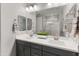 Bright bathroom featuring a double vanity, sleek gray cabinetry, and a large mirror reflecting a glass-enclosed shower at 18768 W Clinton St, Surprise, AZ 85388