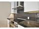 Modern kitchen with sleek black backsplash, stainless steel range hood, and white cabinets at 1955 E Greenway Rd, Phoenix, AZ 85022