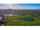 Picturesque golf course aerial featuring lush greens, water features, and scenic mountain backdrop at 6959 E Red Hawk Cir, Mesa, AZ 85207