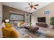Cozy staged living room with stylish furniture, large windows, and a ceiling fan at 6959 E Red Hawk Cir, Mesa, AZ 85207